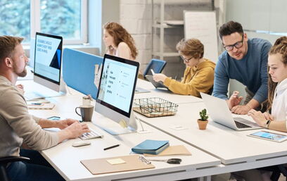 Team arbeitet an Computern und Tablets in einem modernen Büro