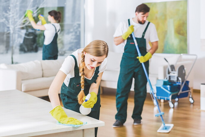 Reinigungsteam putzt Wohnung mit Handschuhen, Mop und Sprühflasche