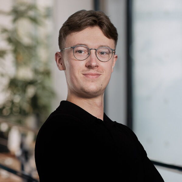 Young man with glasses and black sweater smiling