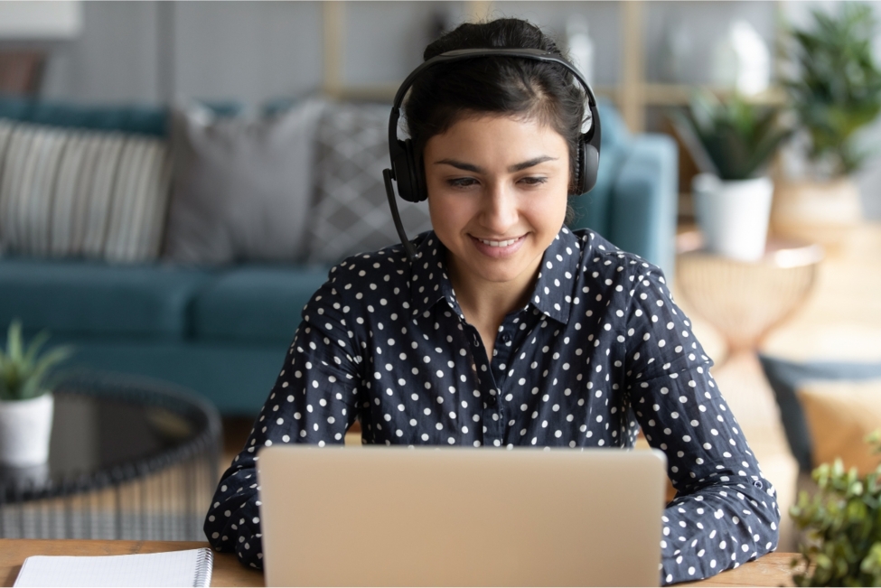 Frau sitzt vor einem Laptop mit einem Headset auf dem Kopf