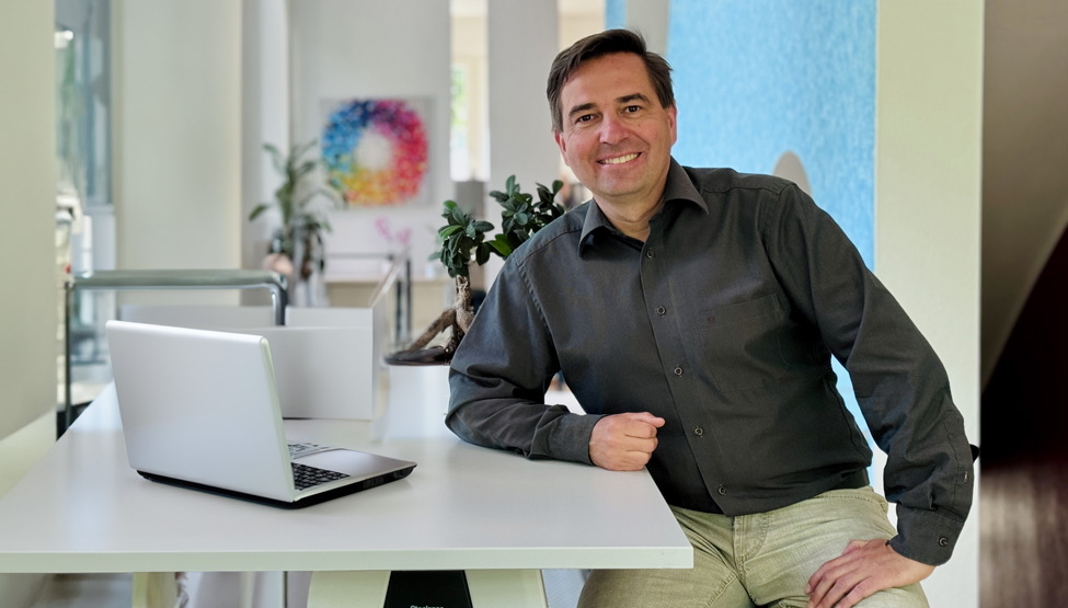 Ronny Büchner sits at a table in front of a laptop