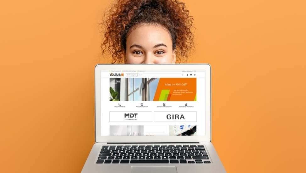 Woman behind a laptop displaying a website on an orange background