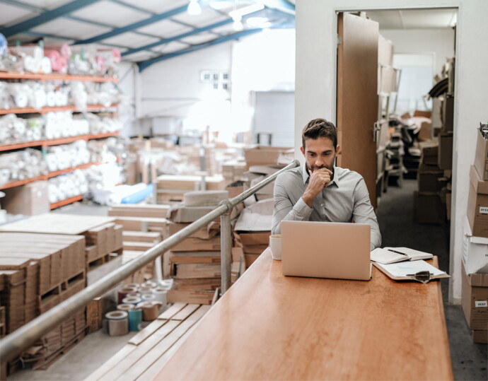 Person in a warehouse working on a laptop