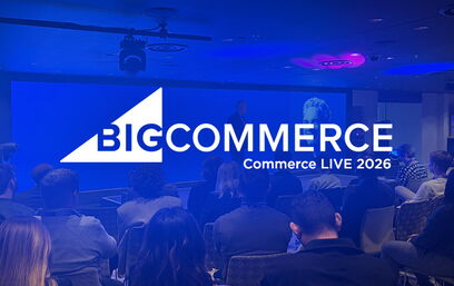 Publikum sitzt in einem Konferenzraum vor Bühne mit großem BigCommerce-Logo und Präsentation.