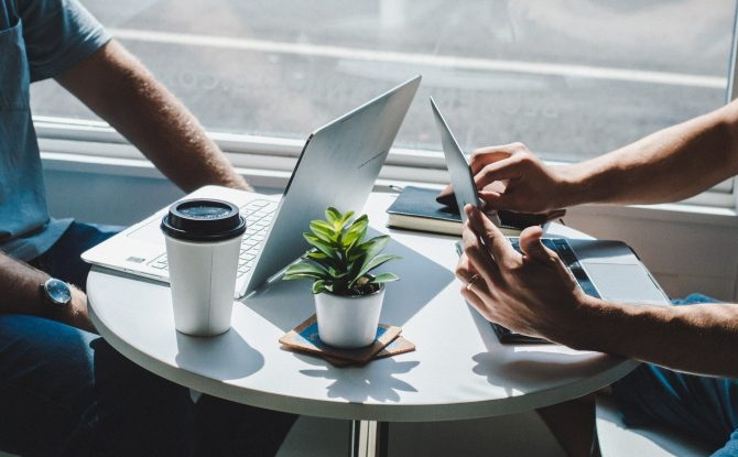 Two people sitting at a table with laptops