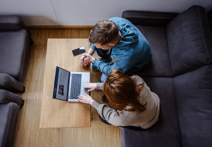 Two people collaborating on a laptop at a table.