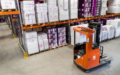 Forklift in a warehouse in front of many goods