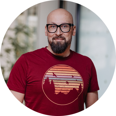 Man with a beard and glasses wearing a red t-shirt with a sunset design